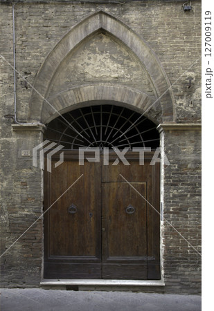 Old wooden door on a house wall. Conceptual image. Wooden Door on an Old House Wall. Architectural Details Worn and Weathered by Time.  127009119