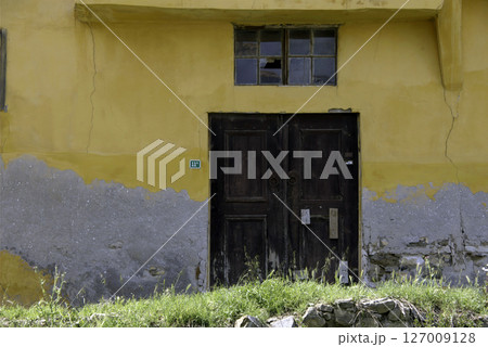 Old wooden door on a house wall. Conceptual image. Wooden Door on an Old House Wall. Architectural Details Worn and Weathered by Time.  127009128