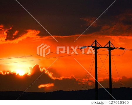 送電線の向こうに夕日が沈むドラマティックな風景 127010560