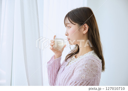 窓際でグラスに入ったジュースを飲む女性 窓際でグラスに入ったジュースを飲む女性 127010710