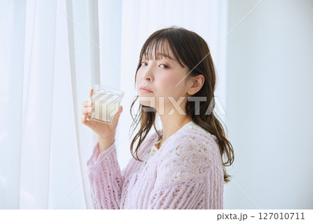 窓際でグラスに入ったジュースを飲む女性 127010711