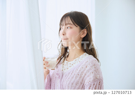 窓際でグラスに入ったジュースを飲む女性 窓際でグラスに入ったジュースを飲む女性 127010713