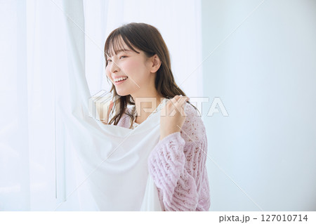 窓際でグラスに入ったジュースを飲む女性 127010714