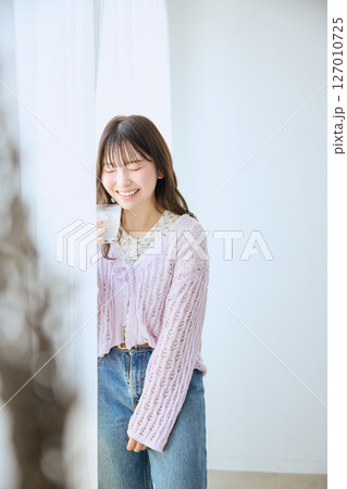 窓際でグラスに入ったジュースを飲む女性 127010725