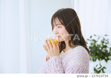 窓際でグラスに入ったジュースを飲む女性 127010739