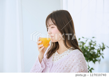 窓際でグラスに入ったジュースを飲む女性 127010740