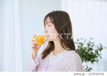 窓際でグラスに入ったジュースを飲む女性 127010742