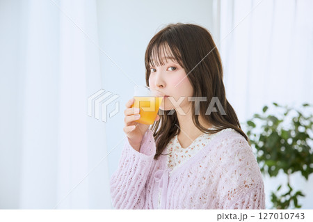 窓際でグラスに入ったジュースを飲む女性 127010743