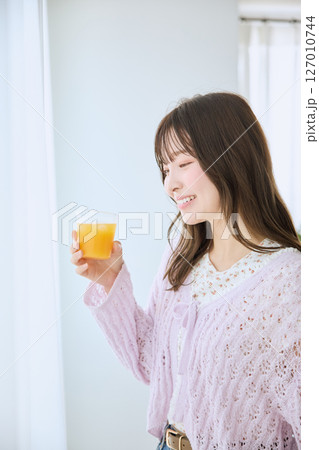 窓際でグラスに入ったジュースを飲む女性 127010744