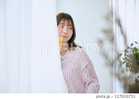 窓際でグラスに入ったジュースを飲む女性 127010751