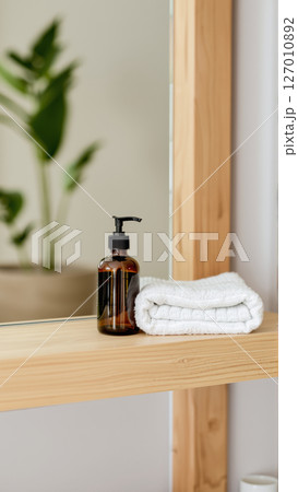 Spa treatment set, wooden shelf with neatly folded towels and dispensers for soap, cream, massage oil 127010892