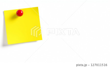 A yellow sheet of paper for notes is attached with a red pushpin to a white wall 127011516
