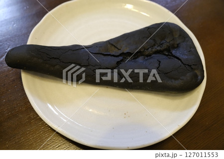ゴジラのしっぽをイメージした黒いナンをお皿にのせる ゴジラのしっぽをイメージした黒いナンをお皿にのせる 127011553