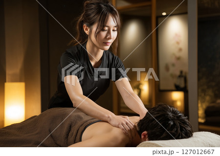 メンズエステで男性の肩こりをほぐす若い女性スタッフ 127012667