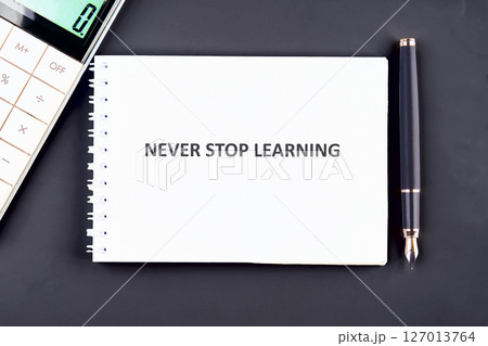 E-learning education concept. NEVER STOP LEARNING written message on a white notebook sheet on a graphite background 127013764