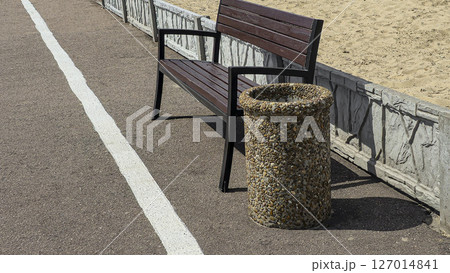 Wooden benches and trash bins line the side of the road in a park recreation area Wooden benches and trash bins line the side of the road in a park recreation area 127014841