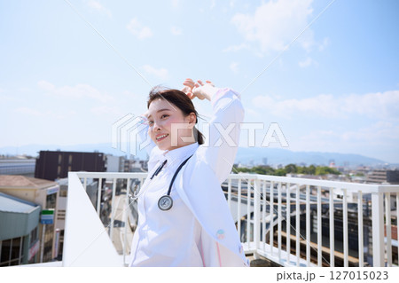 病院の屋上で空を見上げる女性医師 病院の屋上で空を見上げる女性医師 127015023