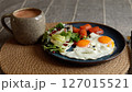 Two sunny eggs with orange yolks rest next to salmon slices, fresh salad with pomegranate seeds, and creamy smoothie in gray mug, highlighting eco-conscious healthy lifestyle meal. 127015521