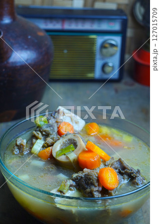 A warm bowl of Indonesian bone marrow soup with carrots and other vegetables, evoking a rustic, traditional Indonesian setting. A warm bowl of Indonesian bone marrow soup with carrots and other vegetables, evoking a rustic, traditional Indonesian setting. 127015709
