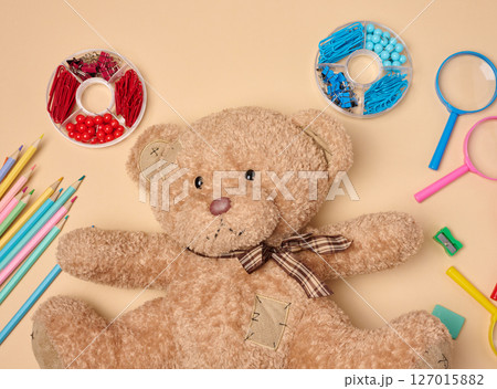 brown teddy bear is surrounded by various colorful school supplies on a neutral background brown teddy bear is surrounded by various colorful school supplies on a neutral background 127015882