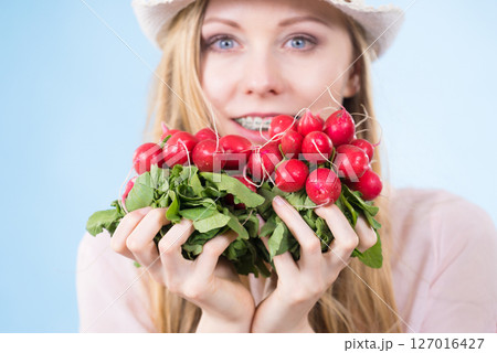 woman holding radish close to face woman holding radish close to face 127016427