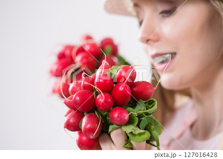 woman holding radish close to face 127016428