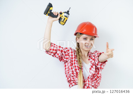 Woman wearing helmet using drill Woman wearing helmet using drill 127016436