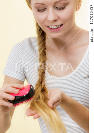 Blonde girl with long braid hair holds brush Blonde girl with long braid hair holds brush 127016457