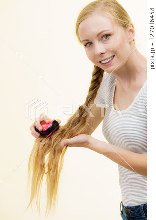Blonde girl with long braid hair holds brush Blonde girl with long braid hair holds brush 127016458