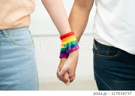 Asian LGBT couple woman holding hand wearing rainbow wristband. 127016737
