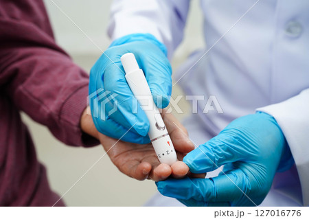 Asian senior woman using lancet pen on senior patient finger for check sample blood sugar level to treatment diabetes. 127016776