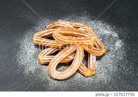 Traditional spanish dessert churros, fried dough pastry dusted with powdered sugar, black background 127017750