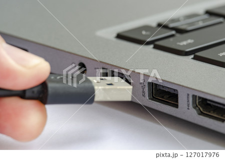 USB being plugged into laptop highlighting risk of unauthorized data transfer or malware USB being plugged into laptop highlighting risk of unauthorized data transfer or malware 127017976