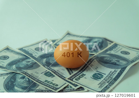401k  Plan note on egg and Pile of US Money. 127019601