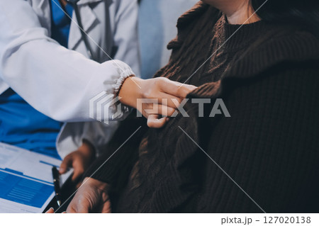 Homecare nursing service and elderly people cardiology healthcare. Close up of young hispanic female doctor nurse check mature caucasian man patient heartbeat using stethoscope during visit Homecare nursing service and elderly people cardiology healthcare. Close up of young hispanic female doctor nurse check mature caucasian man patient heartbeat using stethoscope during visit 127020138