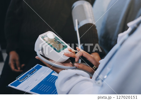 Doctor using Blood pressure monitor and stethoscope checking measuring arterial blood pressure on arm to a patient in the hospital, healthcare and medical concept Doctor using Blood pressure monitor and stethoscope checking measuring arterial blood pressure on arm to a patient in the hospital, healthcare and medical concept 127020151