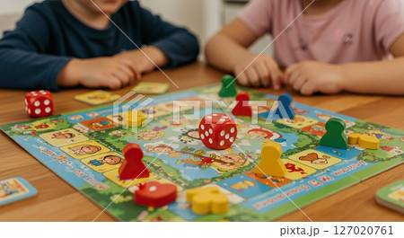 Fun family board game with colorful dice and playful characters on a wooden table 127020761