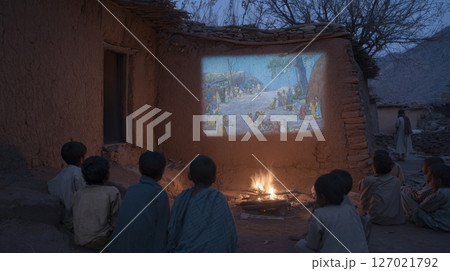 Tribal kids watch an animated film in their native language by firelight and digital glow 127021792