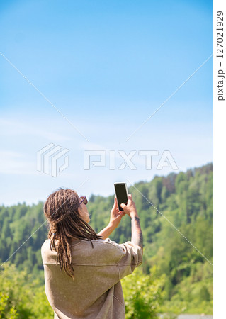 Woman Tourist Capturing View of Mountain Landscape with Smartphone. Travel and Photography Concept. 127021929