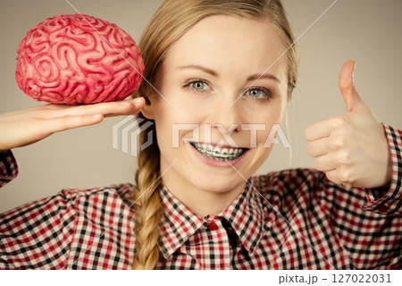Woman thinking and holding fake brain Woman thinking and holding fake brain 127022031