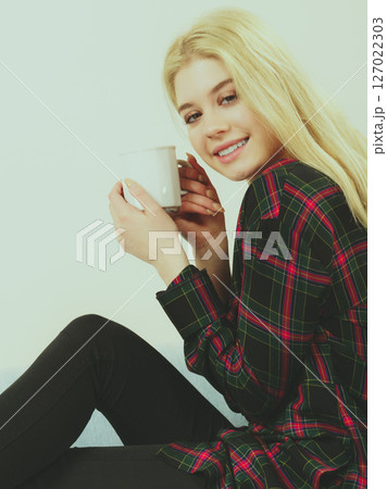 Teenage woman sitting on sofa with mug Teenage woman sitting on sofa with mug 127022303