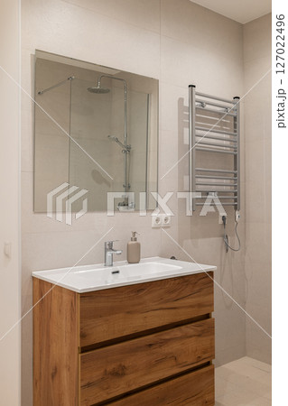 Close-up of bathroom vanity with wood drawers, white ceramic sink and chrome faucet under mirror Close-up of bathroom vanity with wood drawers, white ceramic sink and chrome faucet under mirror 127022496