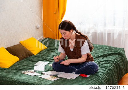 Young woman reviewing expenses and making economic adjustments to maximize savings. concept of financial security and investment awareness. Mid shot Young woman reviewing expenses and making economic adjustments to maximize savings. concept of financial security and investment awareness. Mid shot 127023343