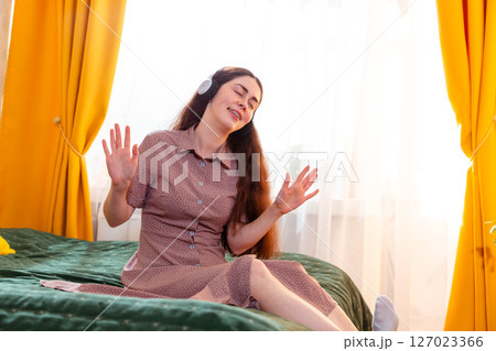 Happy young woman in headphones, smiling while listening to her playlist. Mid shot Happy young woman in headphones, smiling while listening to her playlist. Mid shot 127023366