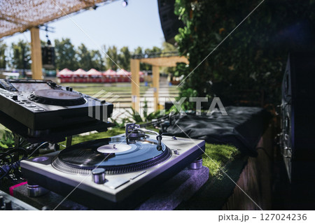 Outdoor DJ Booth with Turntable and Professional Audio Equipment at Music Festival Outdoor DJ Booth with Turntable and Professional Audio Equipment at Music Festival 127024236