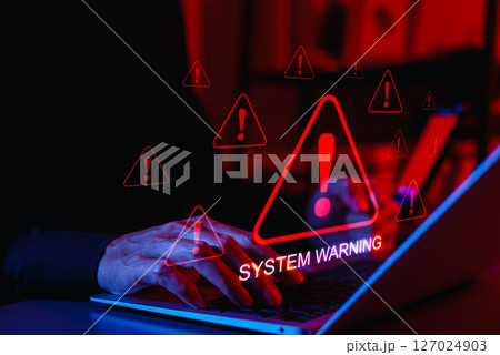 System Warning Alert and Cybersecurity Threat Concept. A person using laptop with system warning and exclamation triangles red, symbolizing cyber security alerts, system failure, and critical threats. 127024903