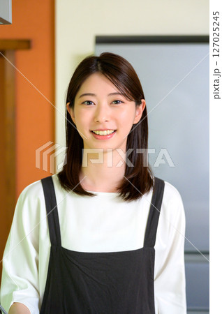 明るい笑顔でキッチンに立つ女性の清潔感あふれる雰囲気 明るい笑顔でキッチンに立つ女性の清潔感あふれる雰囲気 127025245