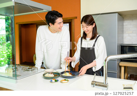 キッチンで笑顔の男女が料理を仕上げる楽しい朝 127025257