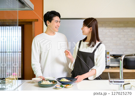 キッチンで会話を楽しむ男女の微笑ましい日常の光景 キッチンで会話を楽しむ男女の微笑ましい日常の光景 127025270