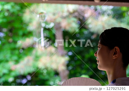 涼しげな風鈴を眺める女性の穏やかな表情 127025291